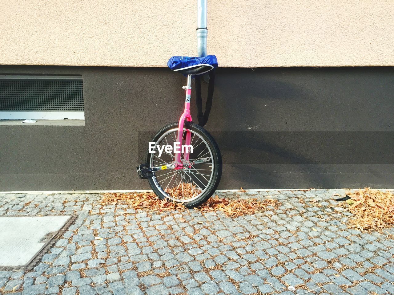 Unicycle parked against brick wall