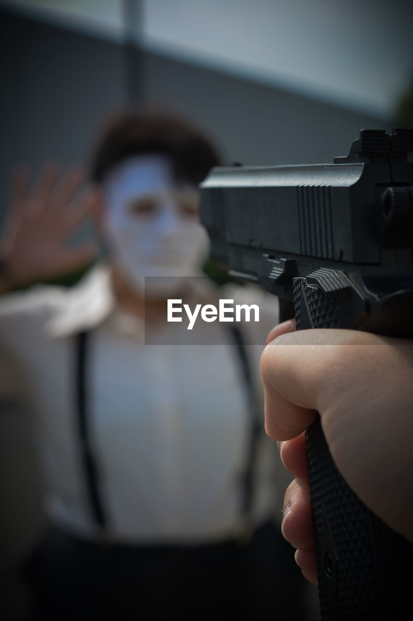 Selective focus of a fake gun being pointed at a masked person