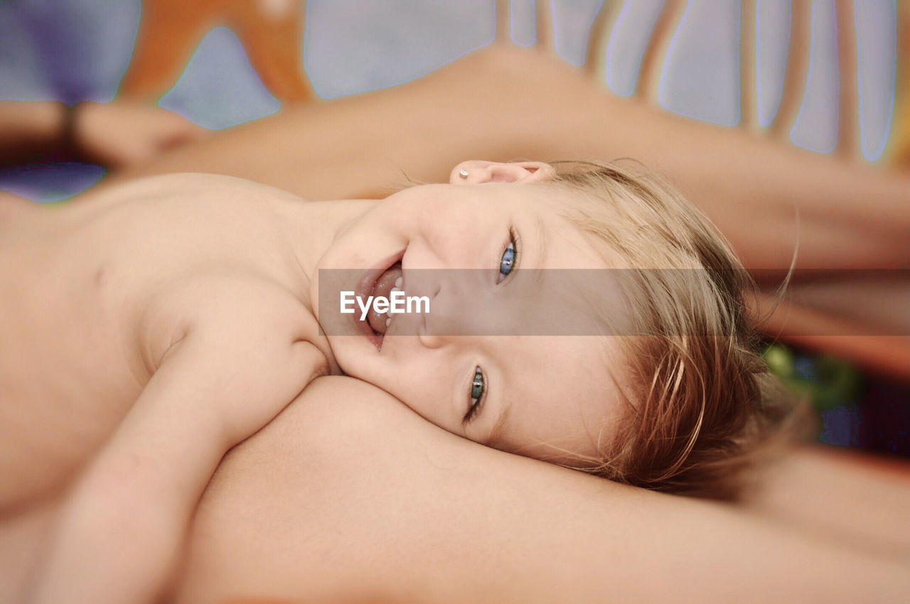 Close-up portrait of a girl lying on mothers legs