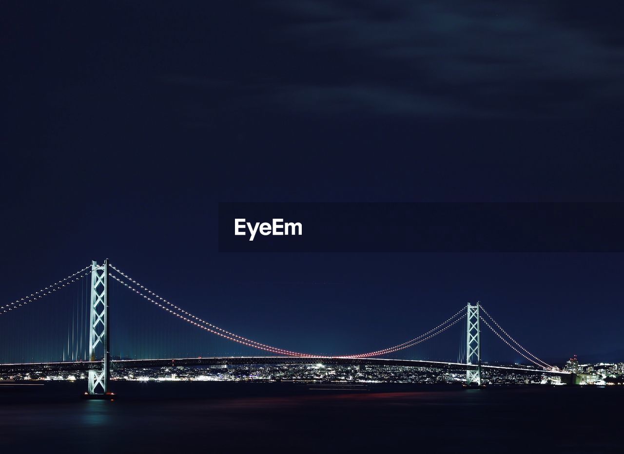 Illuminated akashi strait bridge over sea against clear sky at night