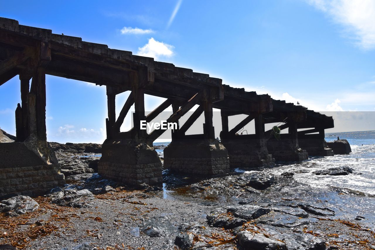 Bridge over sea shore against sky