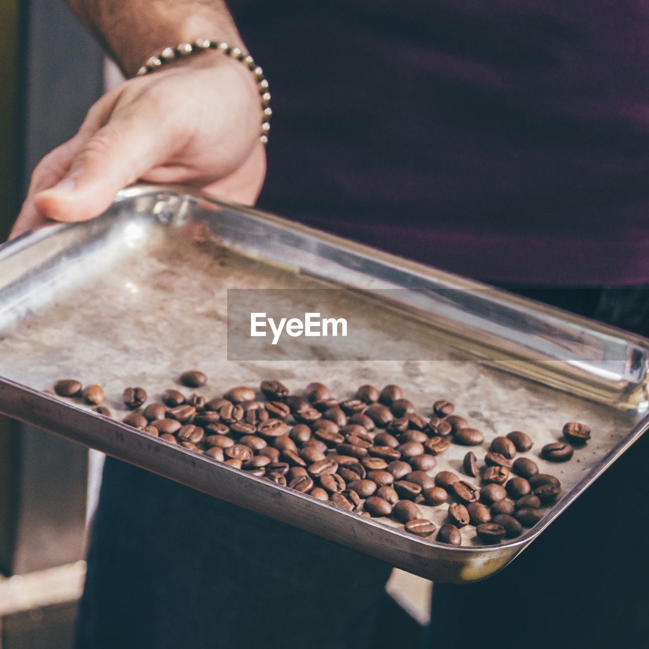 Man holding tray with coffe beans
