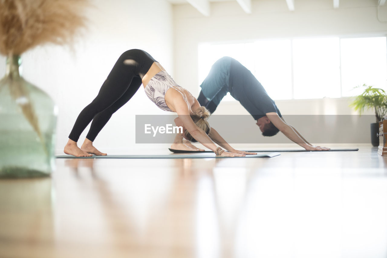 A couple in downward facing dog position during yoga.