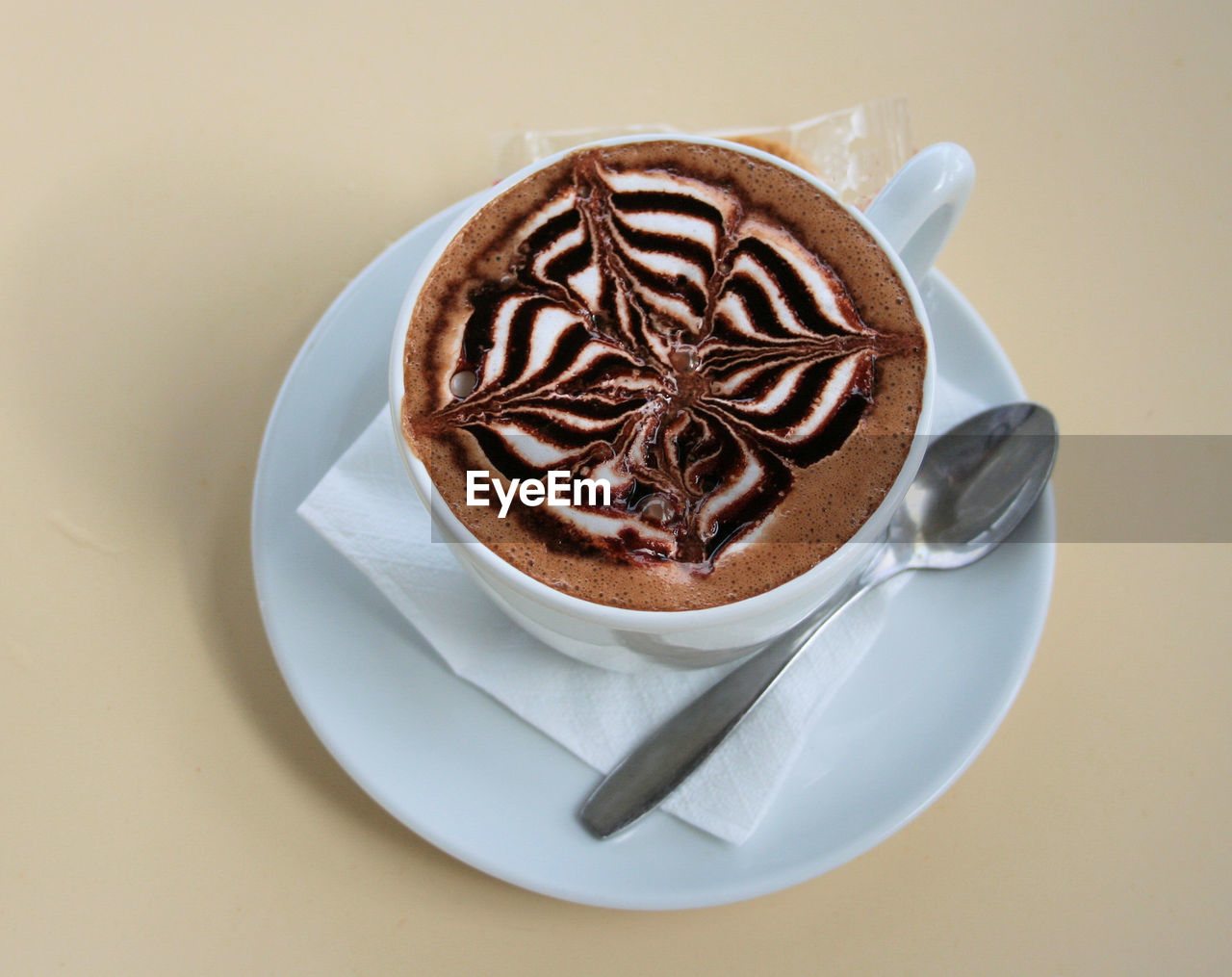 COFFEE CUP ON TABLE AGAINST WHITE WALL