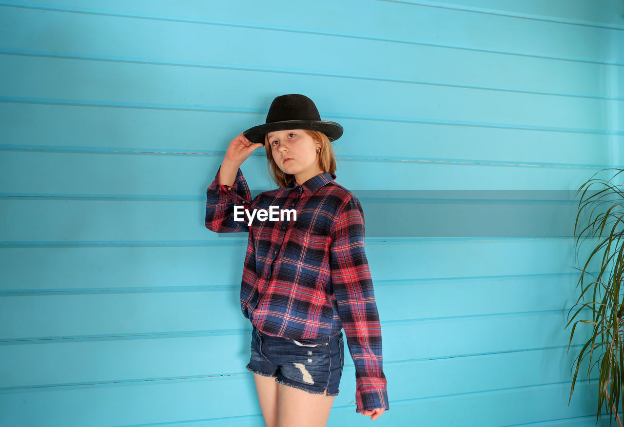 Portrait of a girl in a hat on a blue wooden background