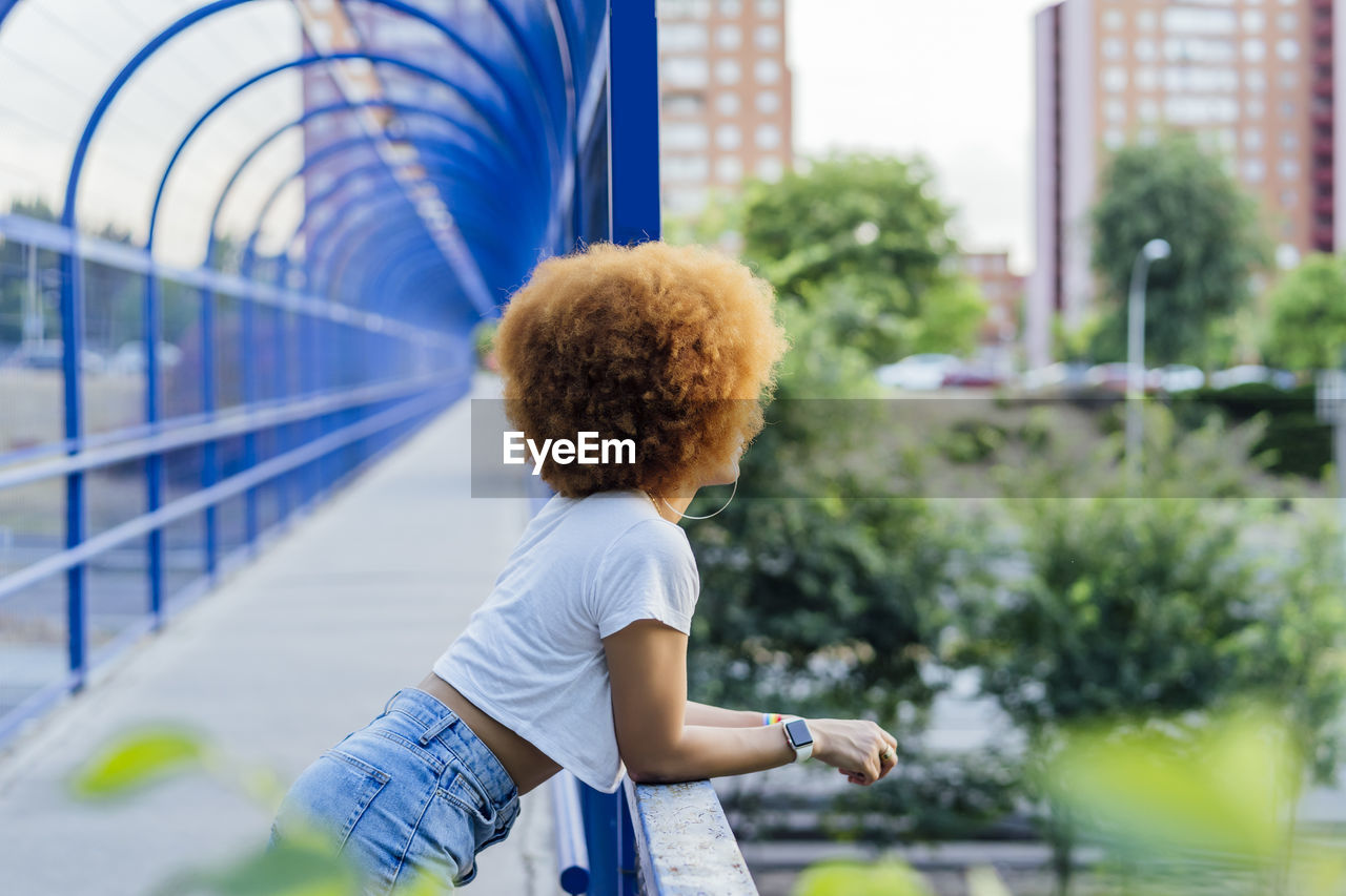 Woman with afro hair leaning on a bridge