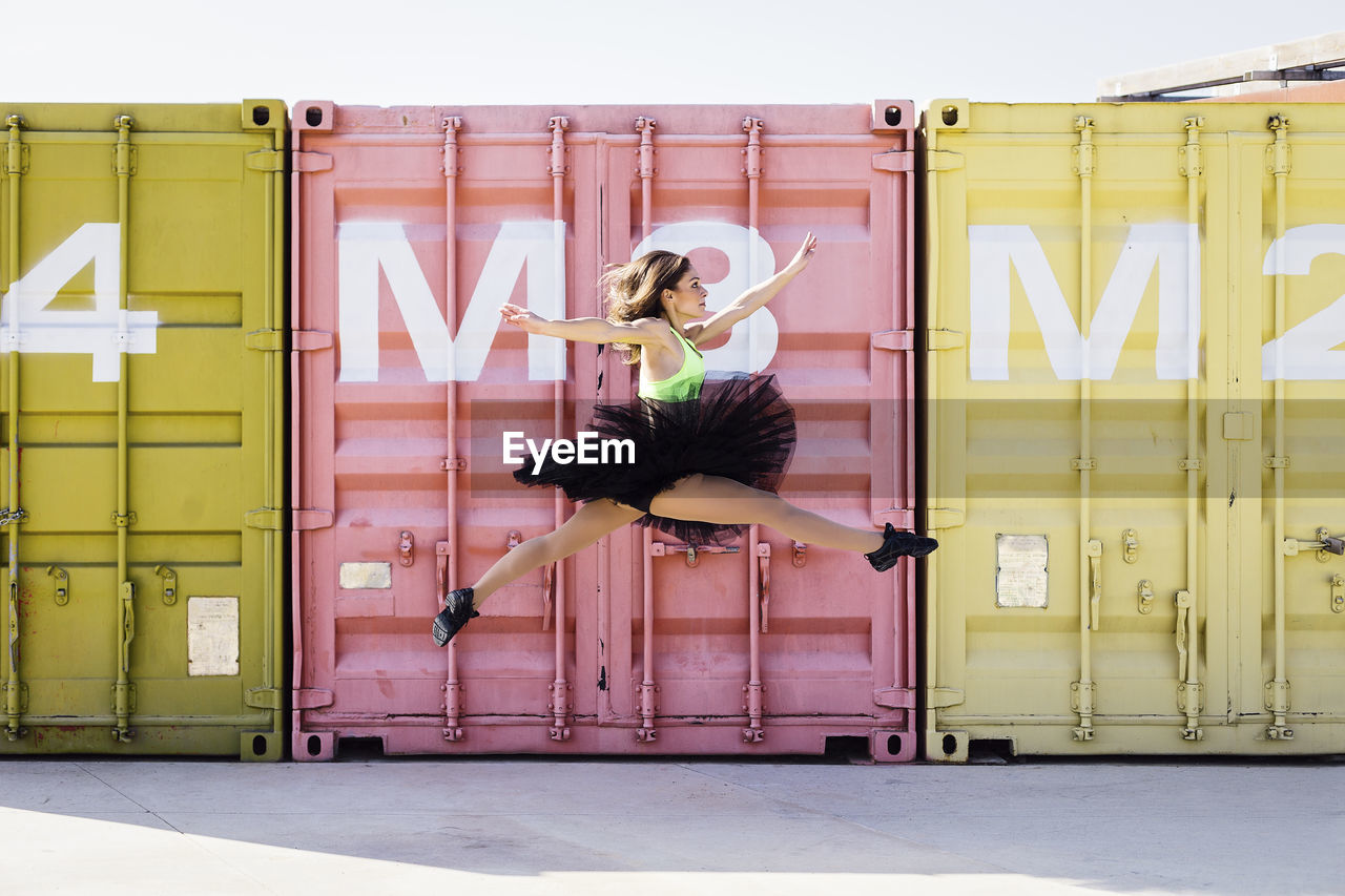 Ballet dancer dancing against cargo containers