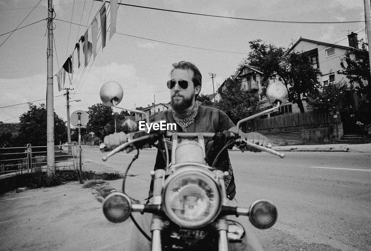 Young man riding motorcycle on road against sky