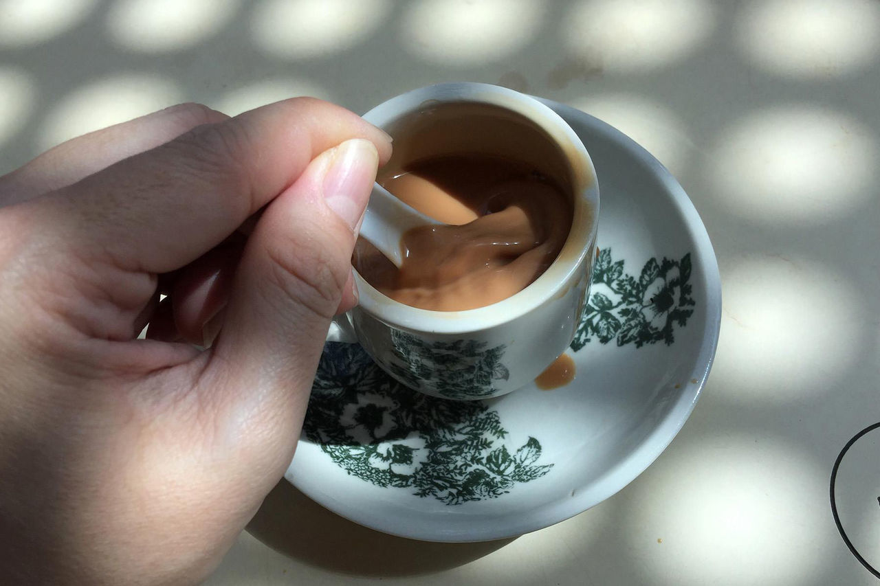 Cropped image of hand mixing tea with spoon in cup