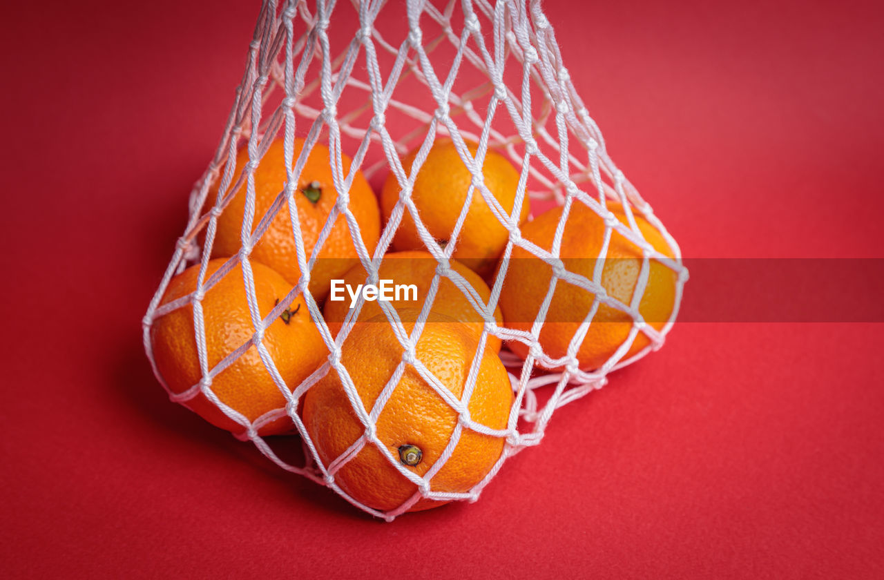 Eco-friendly mesh with tangerines on a red festive background. feast of the nativity of christ.