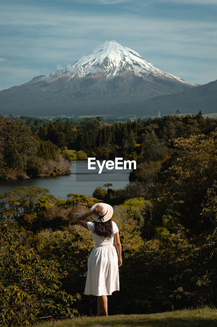 REAR VIEW OF WOMAN ON SNOWCAPPED MOUNTAIN