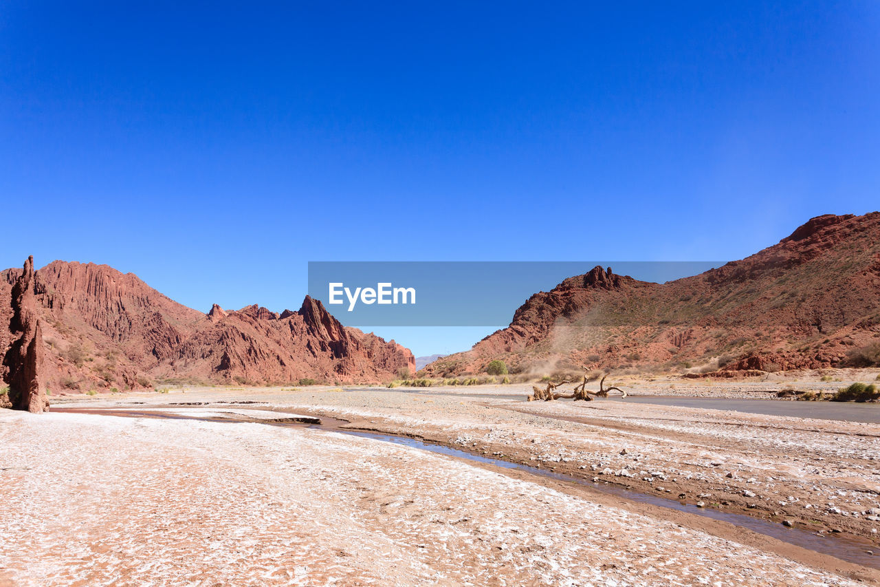 SCENIC VIEW OF ROAD AMIDST DESERT AGAINST CLEAR BLUE SKY