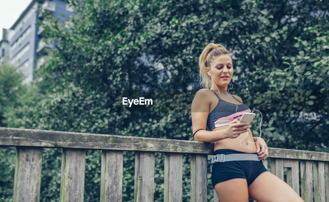 Beautiful young woman using phone on boardwalk