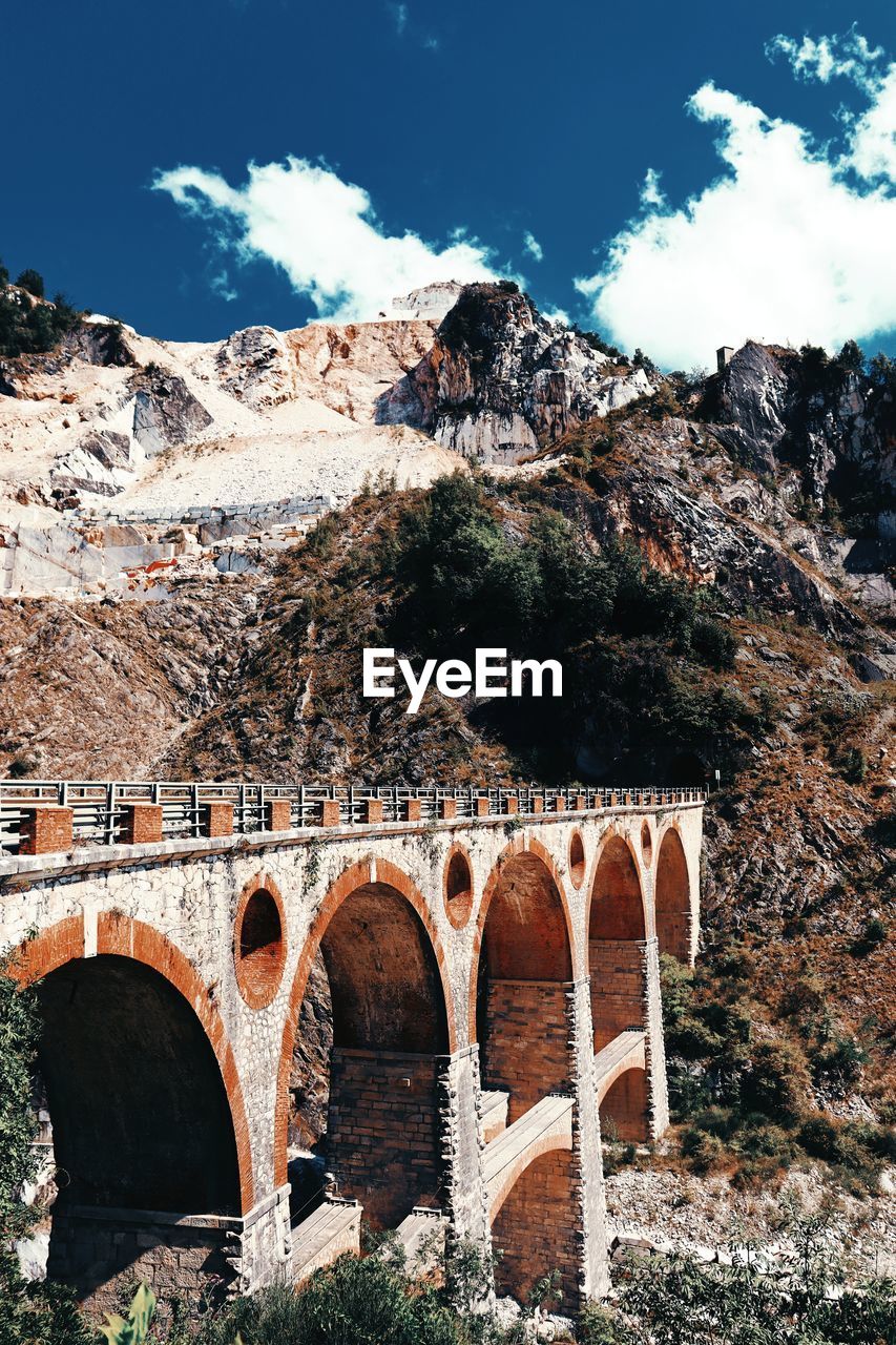 Arch bridge over mountain against sky