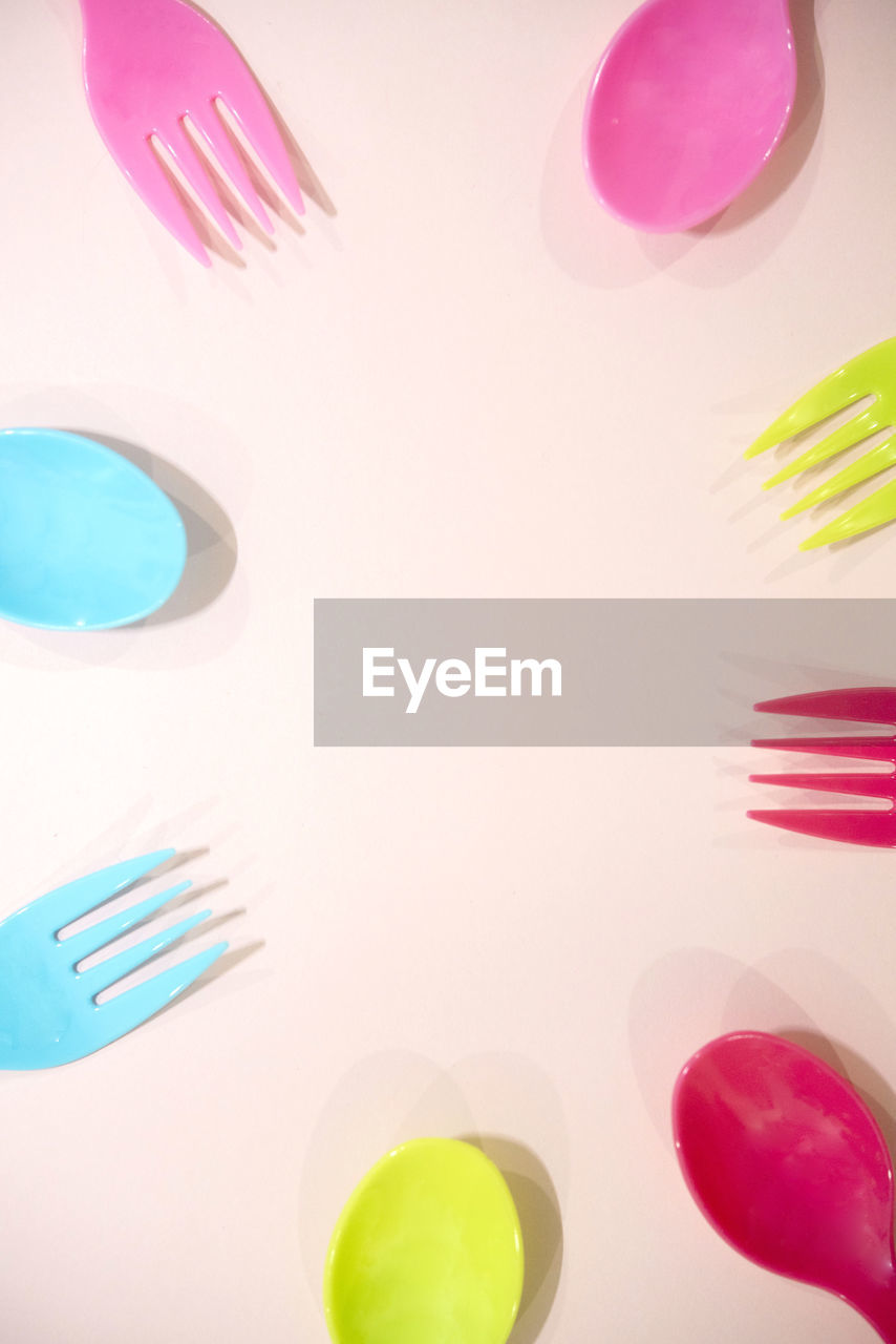 Close-up of colorful disposable forks and spoons on colored background