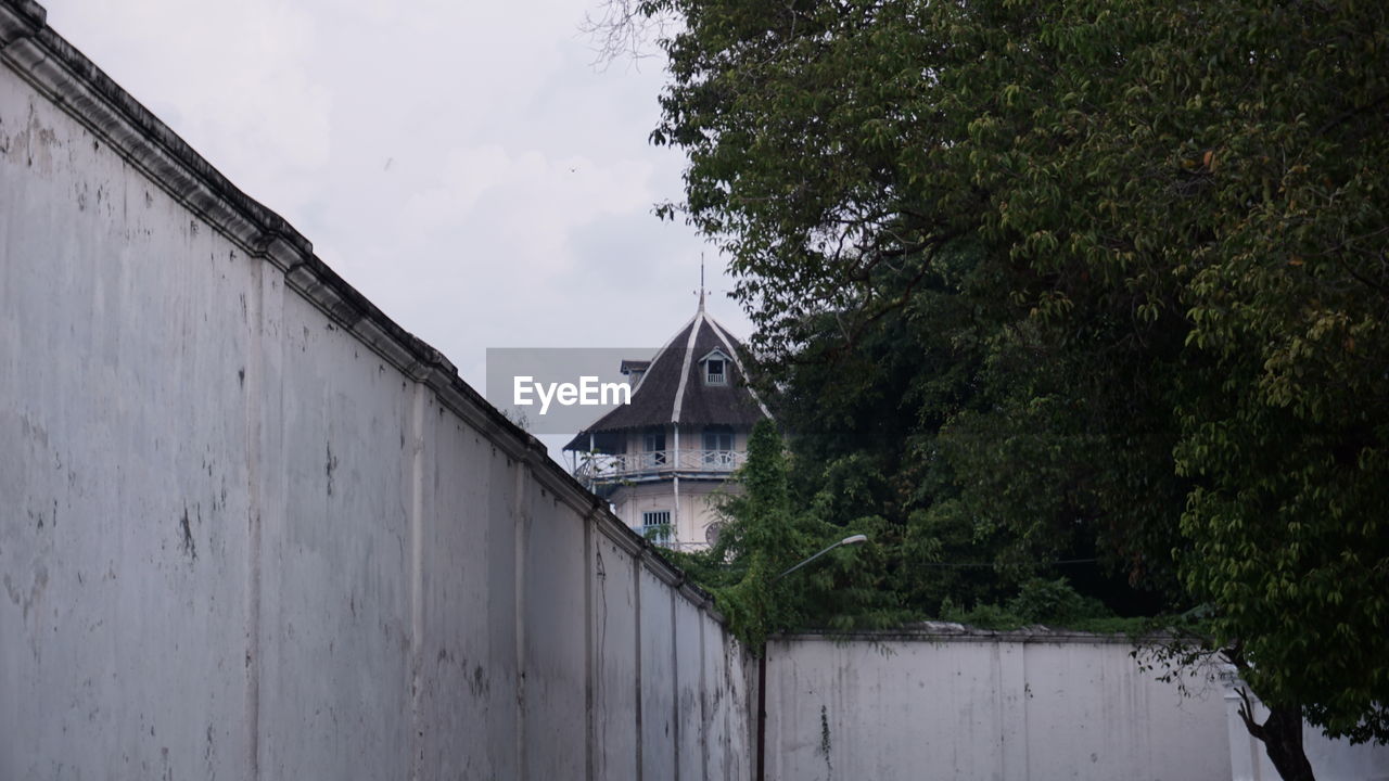 LOW ANGLE VIEW OF BUILDING AMIDST TREES AGAINST SKY