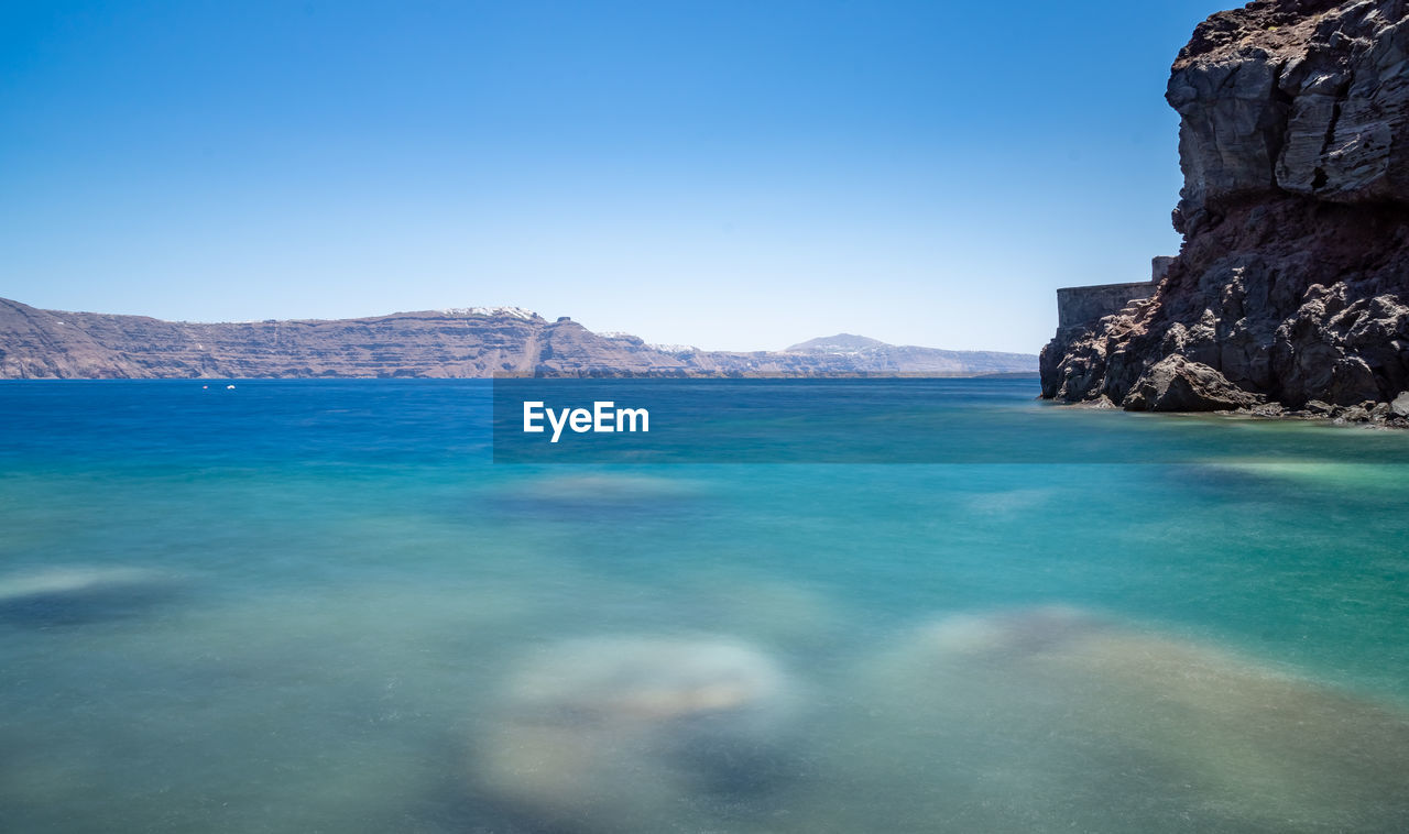 View from the beach of the cliff and the santorini caldera. sunny day, sky without clouds