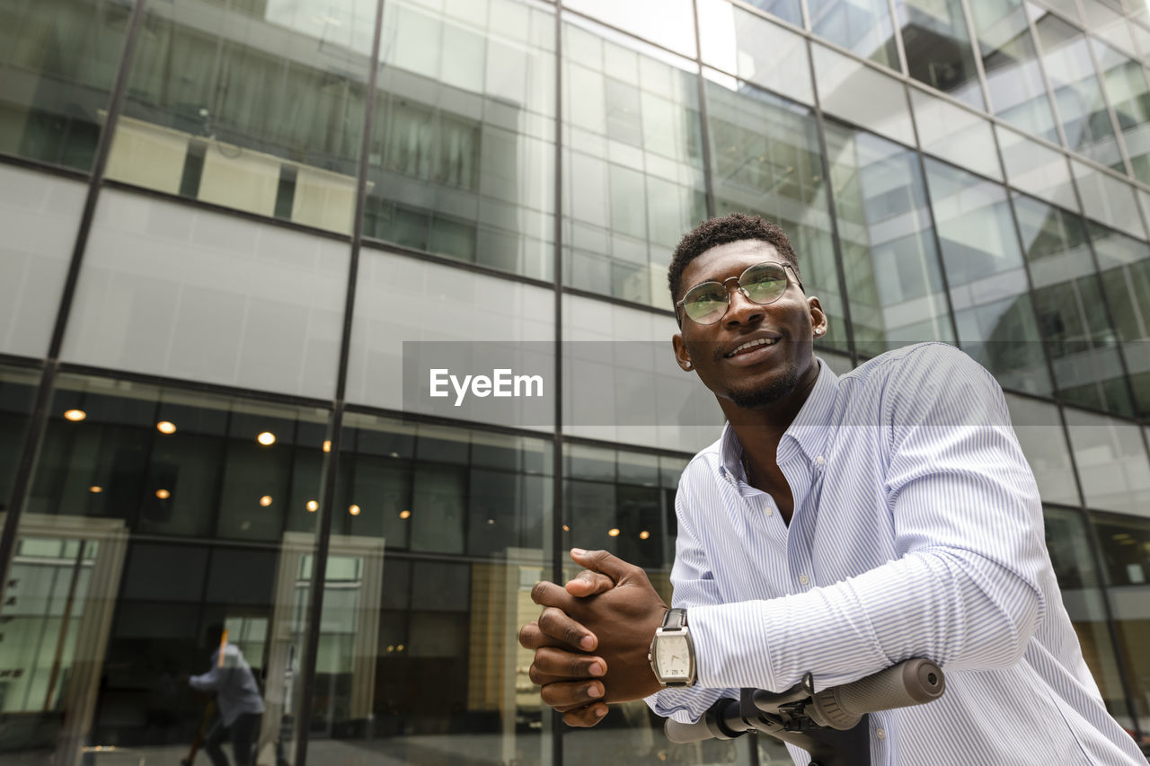 Thoughtful man with hands clasped in front of building