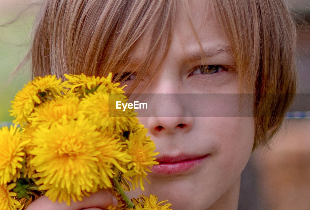 Close-up portrait of boy with yellow flowers