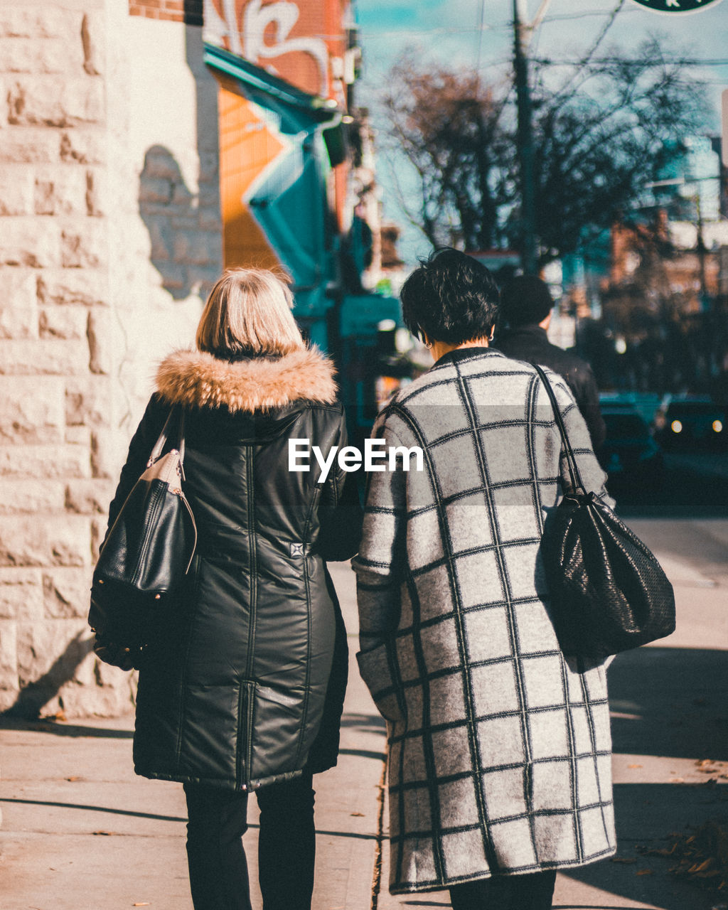 REAR VIEW OF MAN AND WOMAN WALKING ON STREET