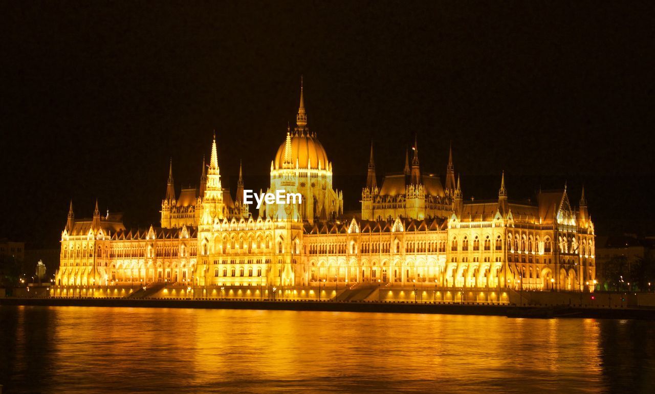 Illuminated hungarian parliament building by danube river at night