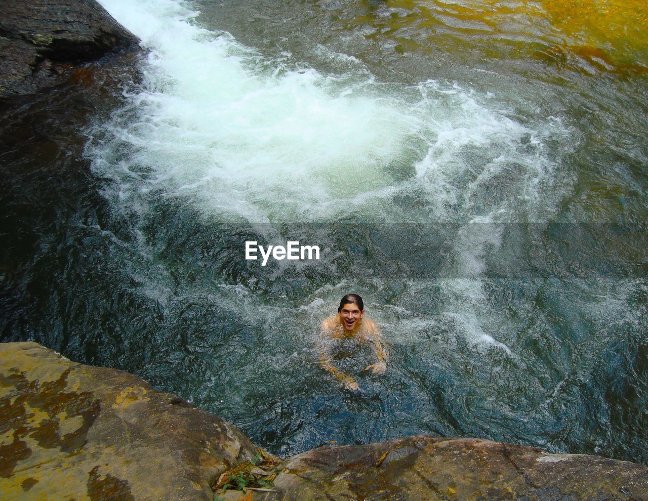 High angle view of happy man swimming in river