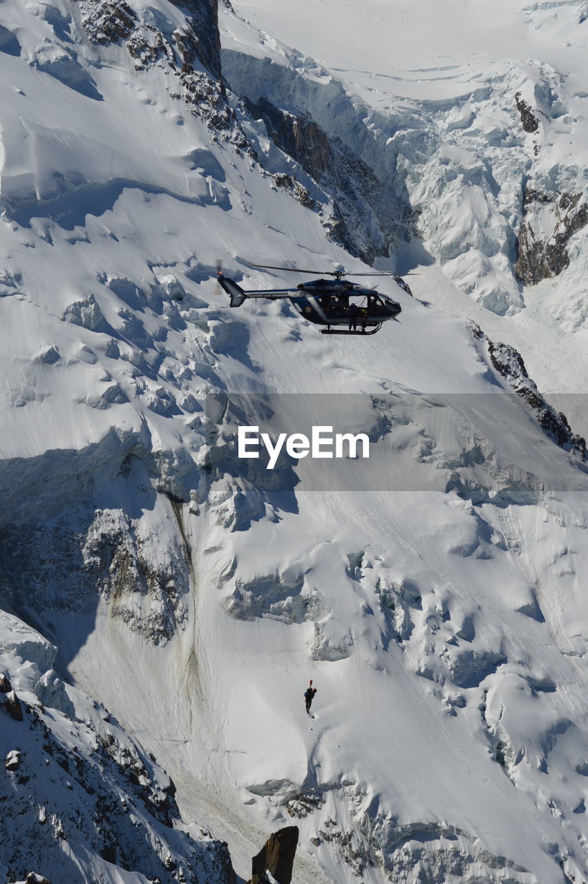 Scenic view of snowcapped mountains against sky with rescue helicopter