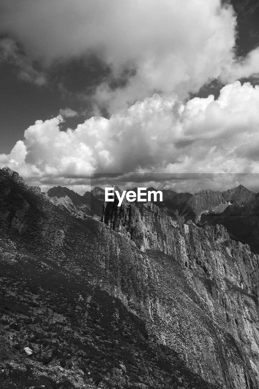 cloud, mountain, sky, environment, landscape, scenics - nature, black and white, beauty in nature, nature, monochrome, mountain range, monochrome photography, rock, land, travel, travel destinations, non-urban scene, outdoors, cloudscape, no people, tranquility, snow, day, tranquil scene, tourism, extreme terrain, activity, mountain peak, dramatic sky, leisure activity, overcast, valley, geology
