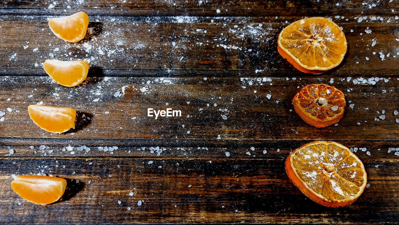 Tangerine slices and dried orange slices in close-up on an old wooden background.