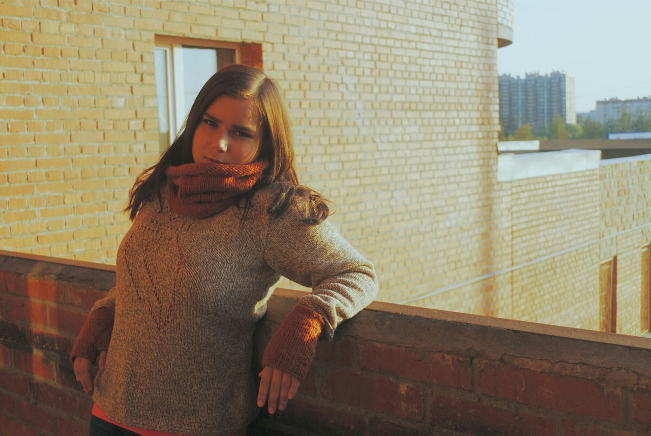 PORTRAIT OF YOUNG WOMAN STANDING ON BRICK WALL