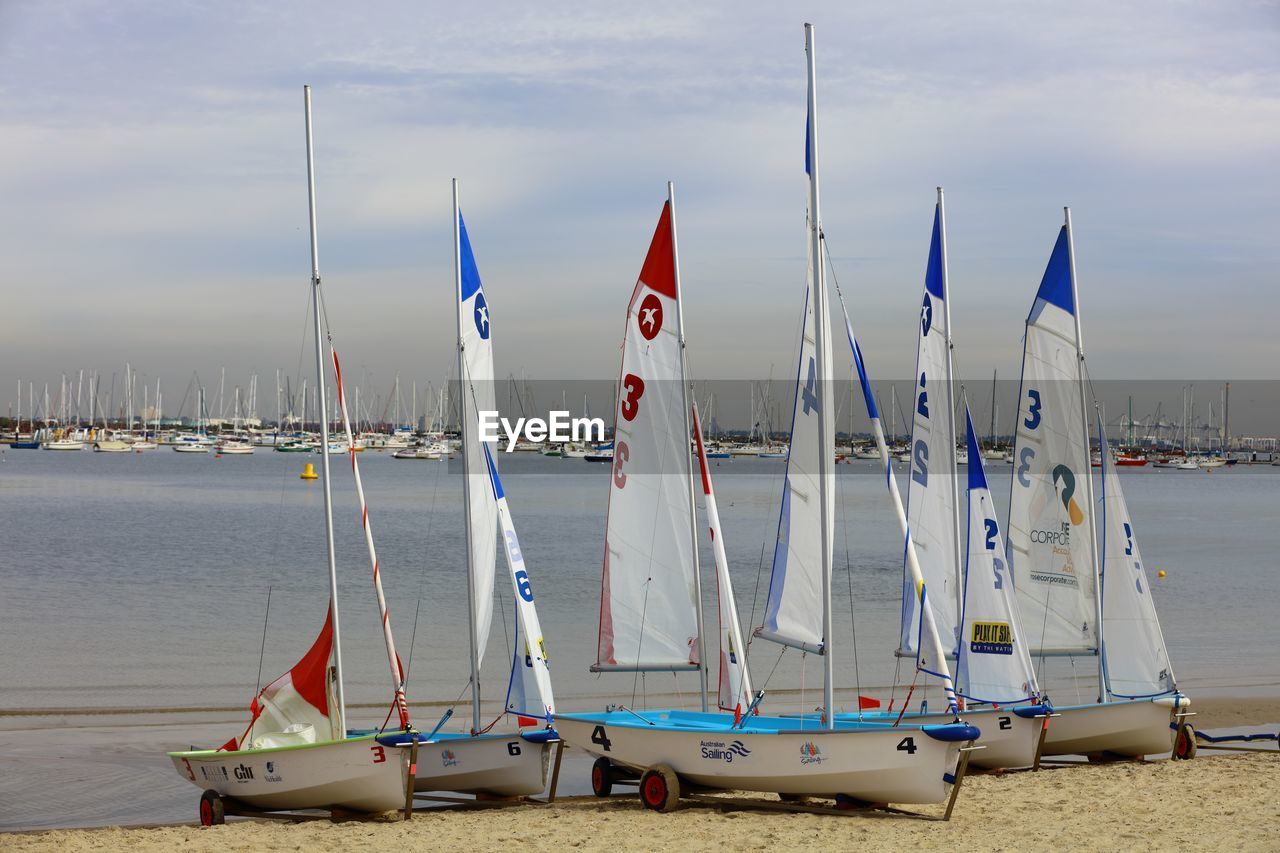 SAILBOATS MOORED IN SEA AGAINST SKY