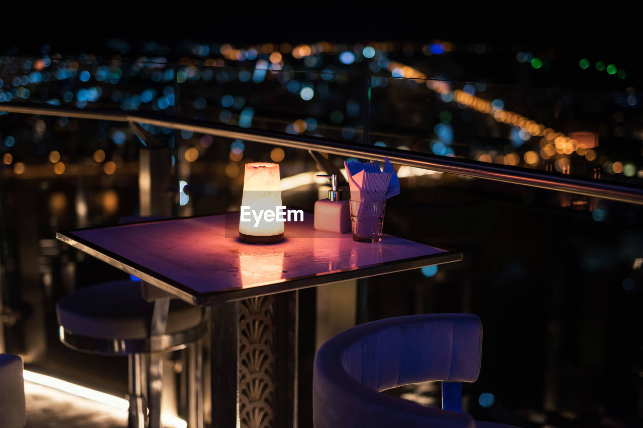 Open air dinner table at rooftop with blur bokeh city light background. luxury pub and restaurant