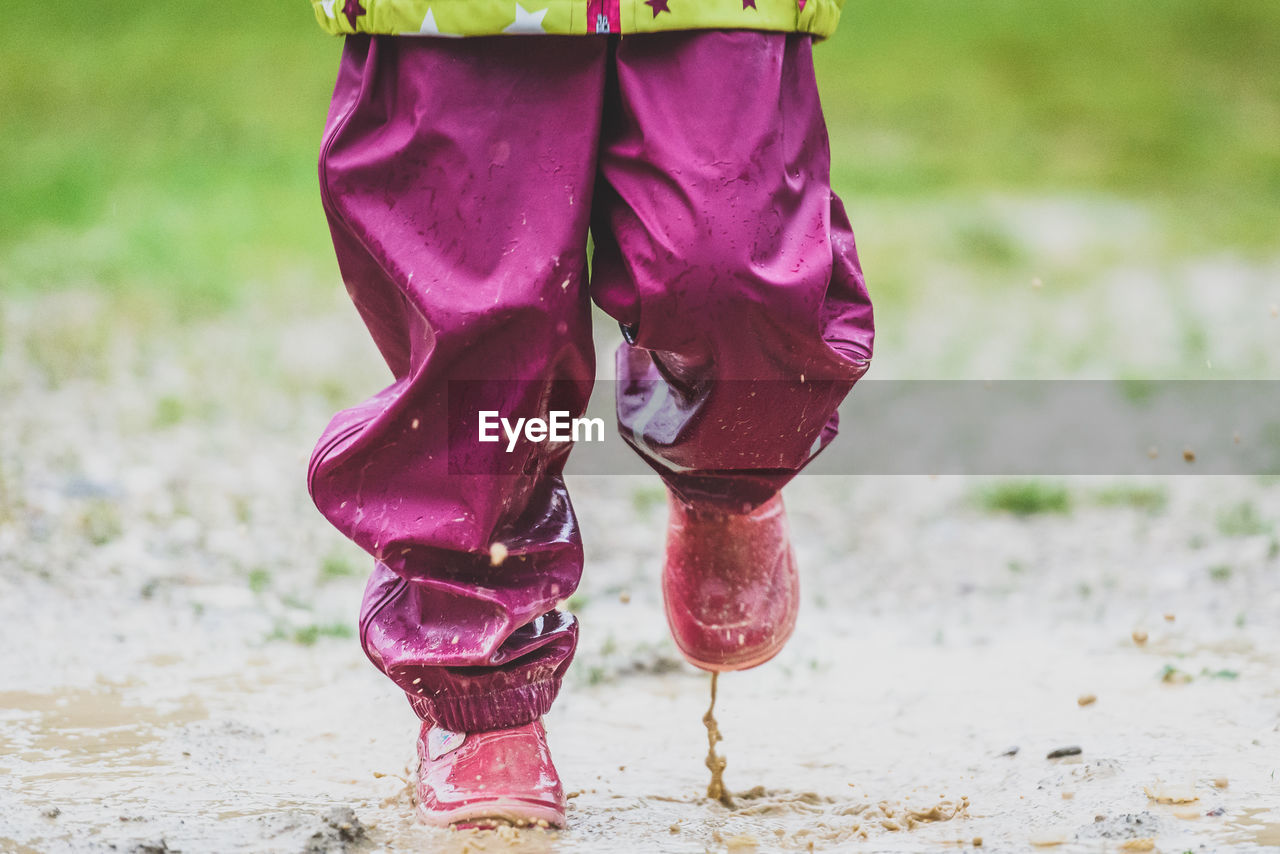 Low section of child playing in puddle on field