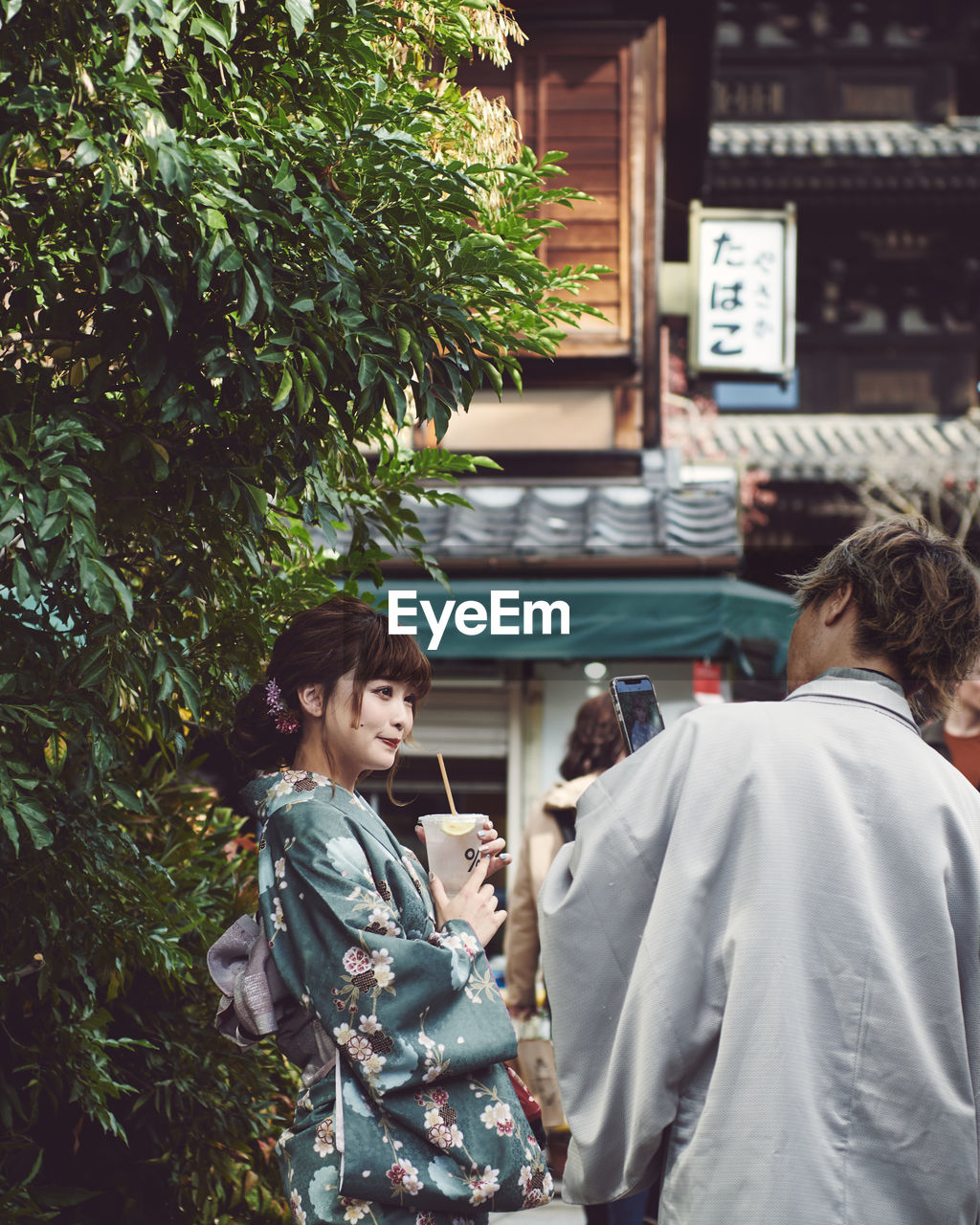 REAR VIEW OF COUPLE STANDING BY PLANTS AT THE ENTRANCE OF A MAN