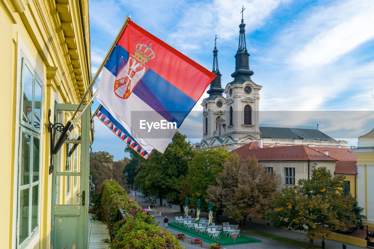 LOW ANGLE VIEW OF FLAGS AND BUILDINGS AGAINST SKY