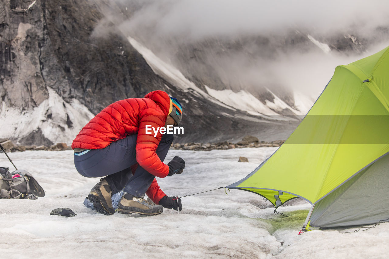 Mountaineer staking tent on glacier in akshayak pass.