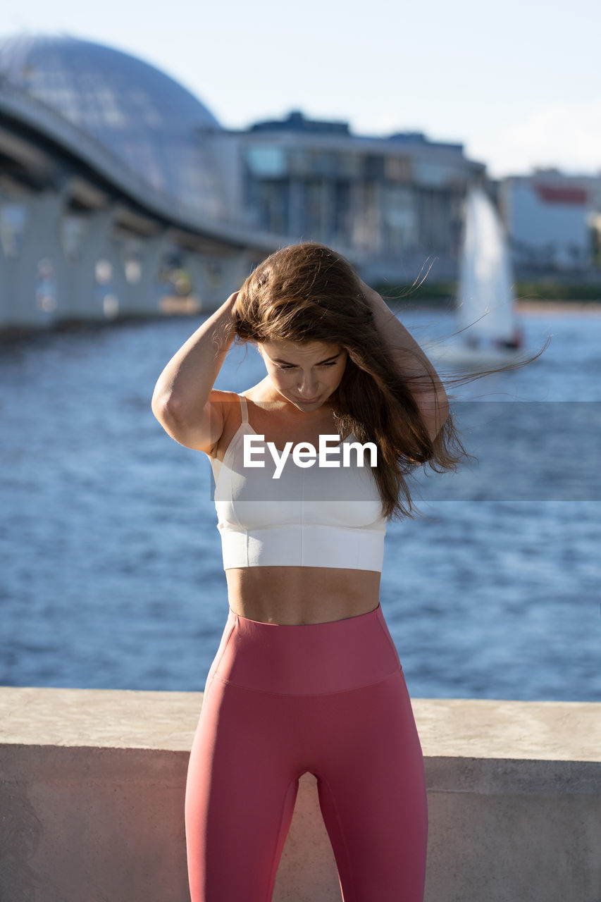 Beautiful woman exercising while standing by bay