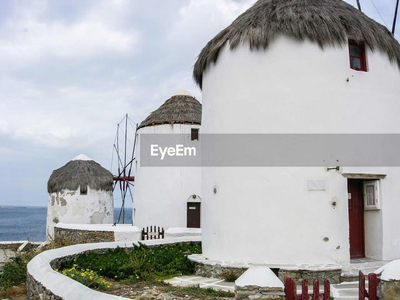 Traditional windmills at mykonos against cloudy sky