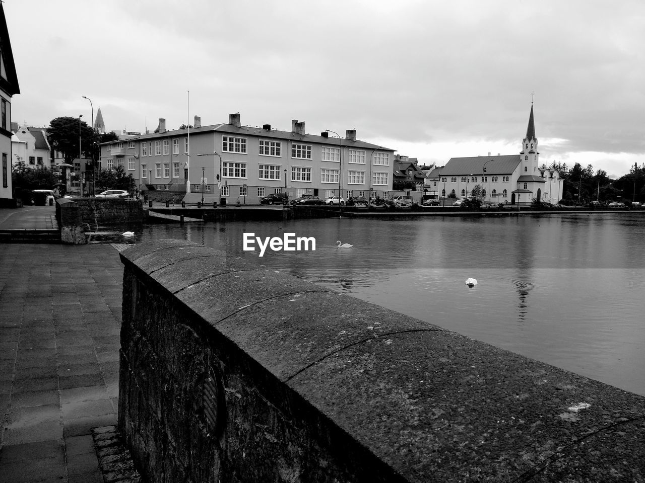 Buildings by river against sky in city