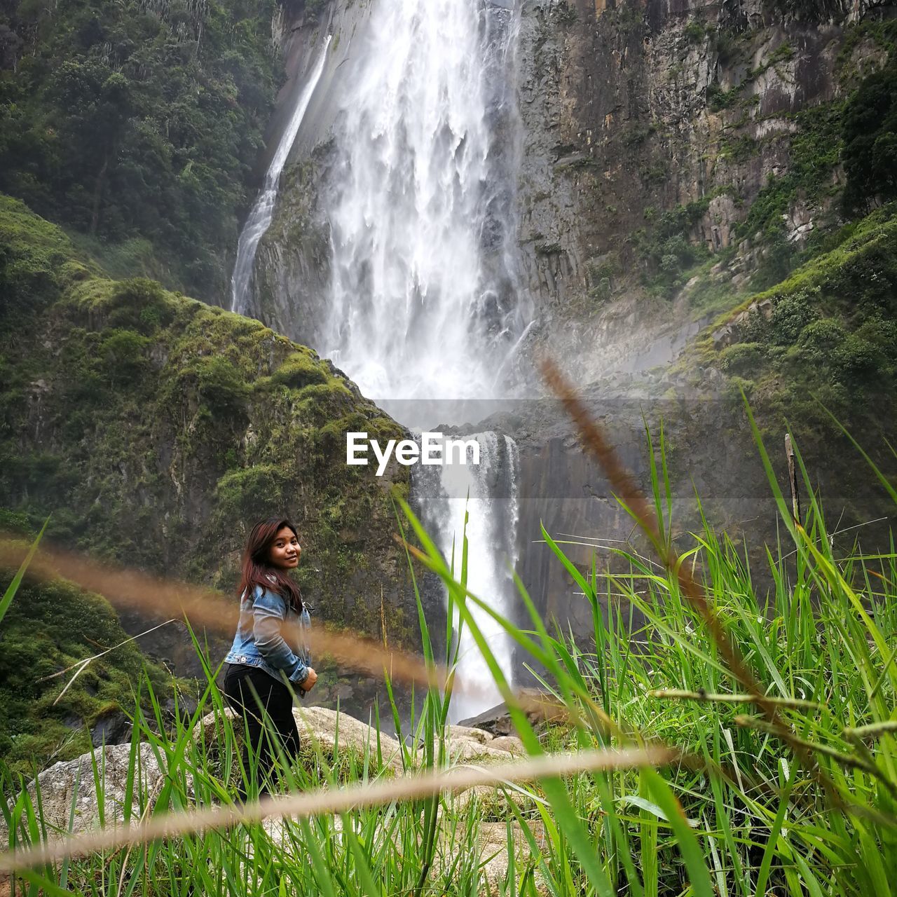 Side view of woman standing by waterfall