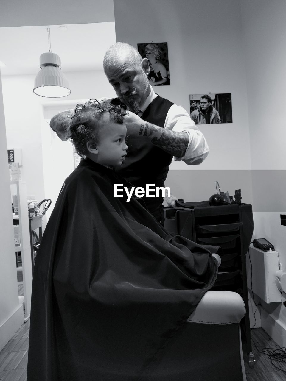 Barber cutting hair of boy at salon