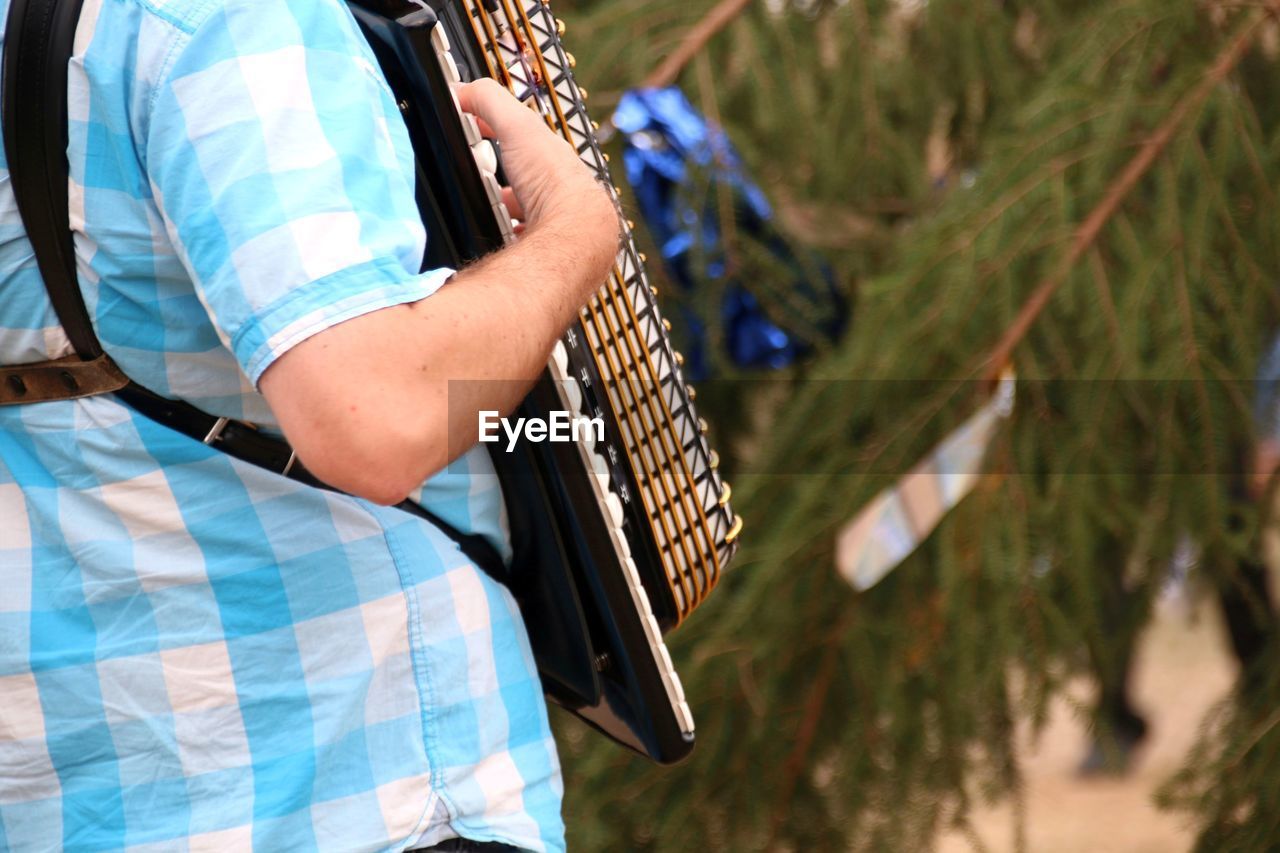 Midsection of man playing accordion while standing outdoors