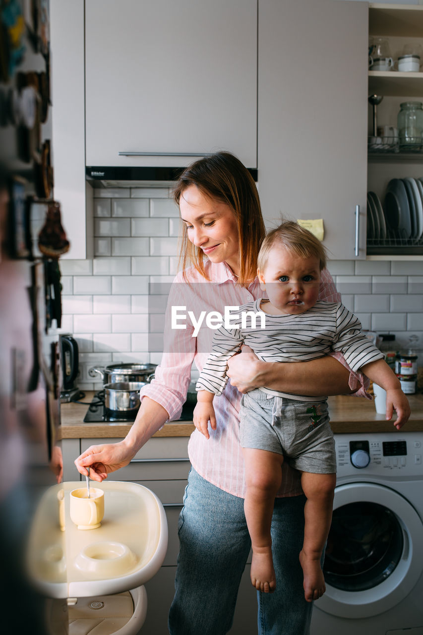 Mom feeds a small child at home with yogurt from a spoon. family concept