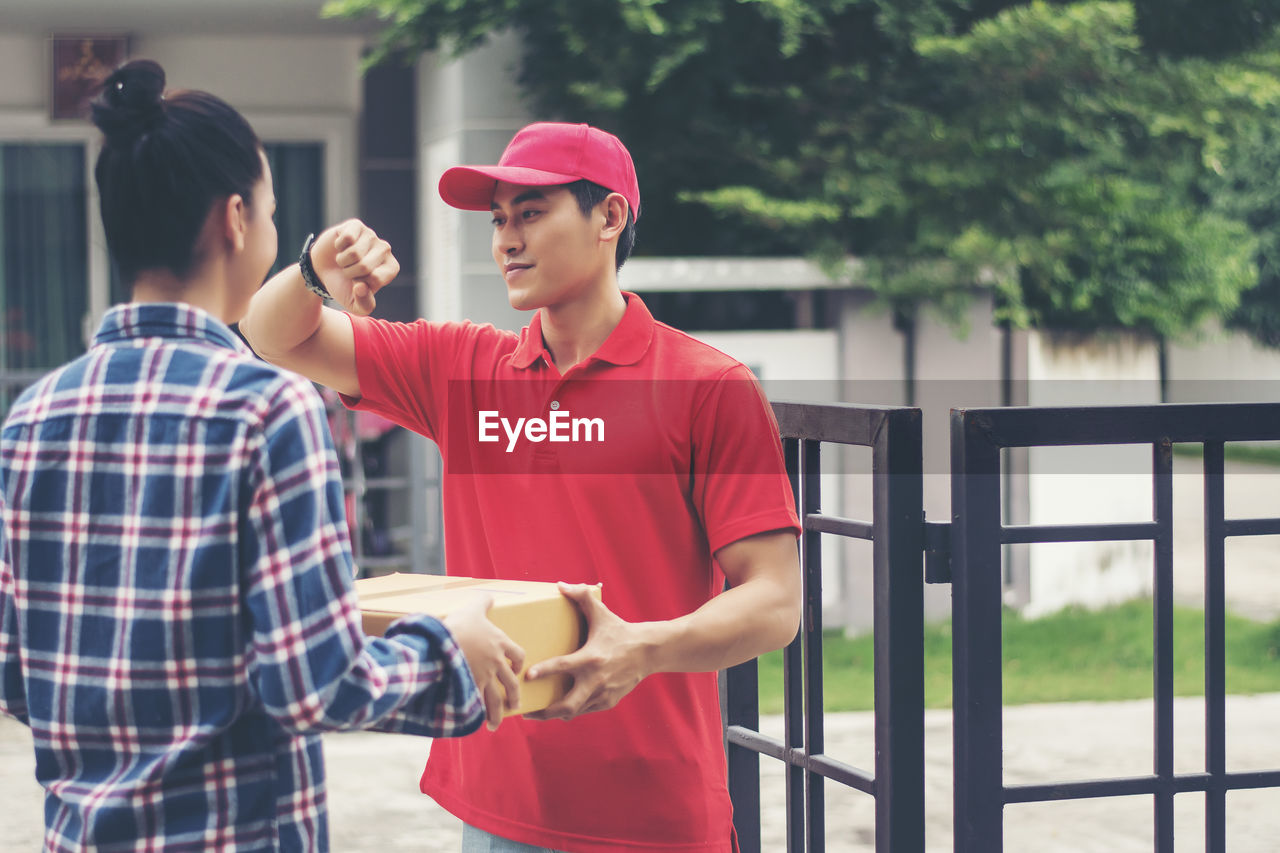 Man delivering package to female customer at gate