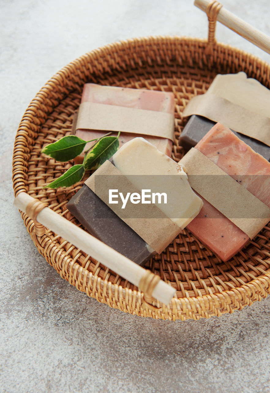 Assorted handmade natural soap bars, massage towel and green leaves. 