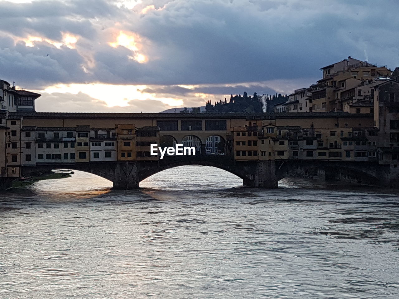 Bridge over river by buildings against sky