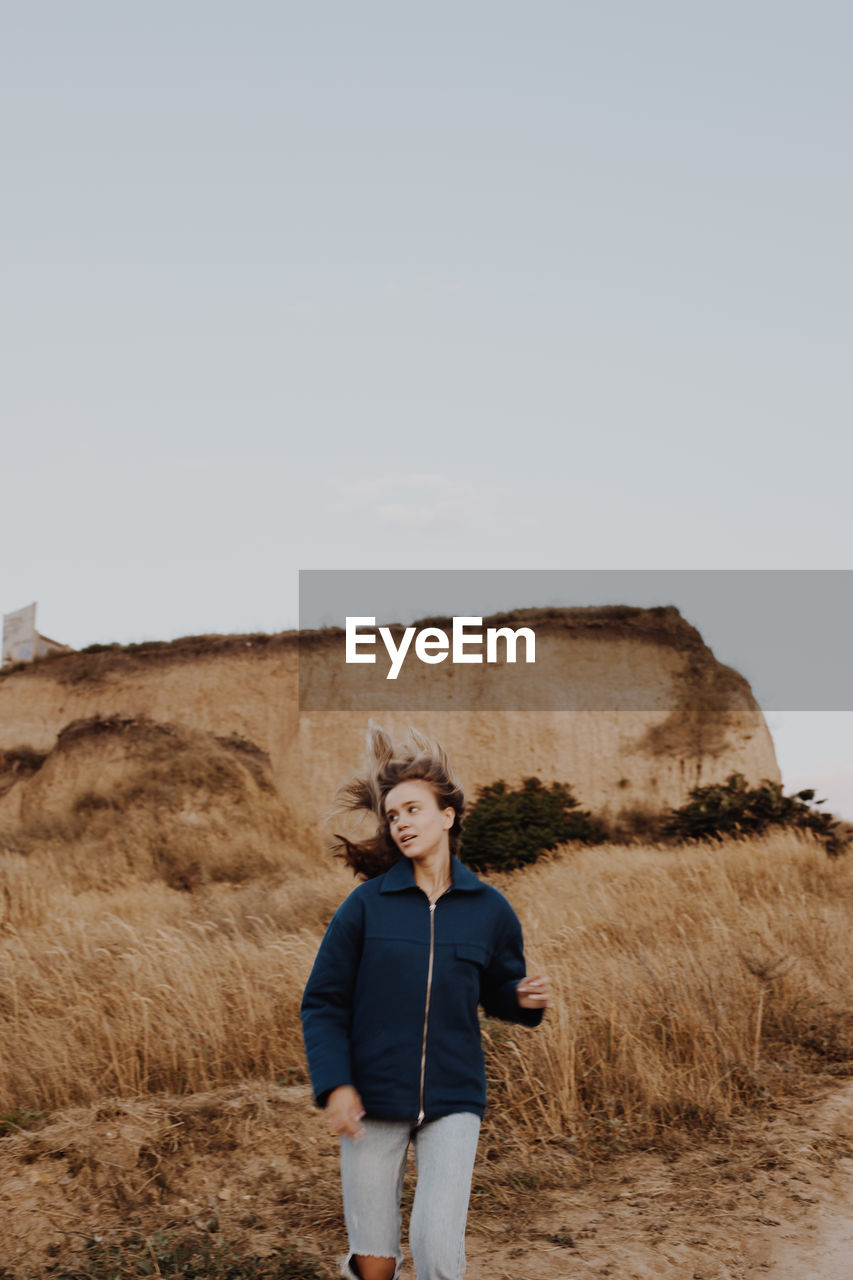 Young woman looking away while walking on land