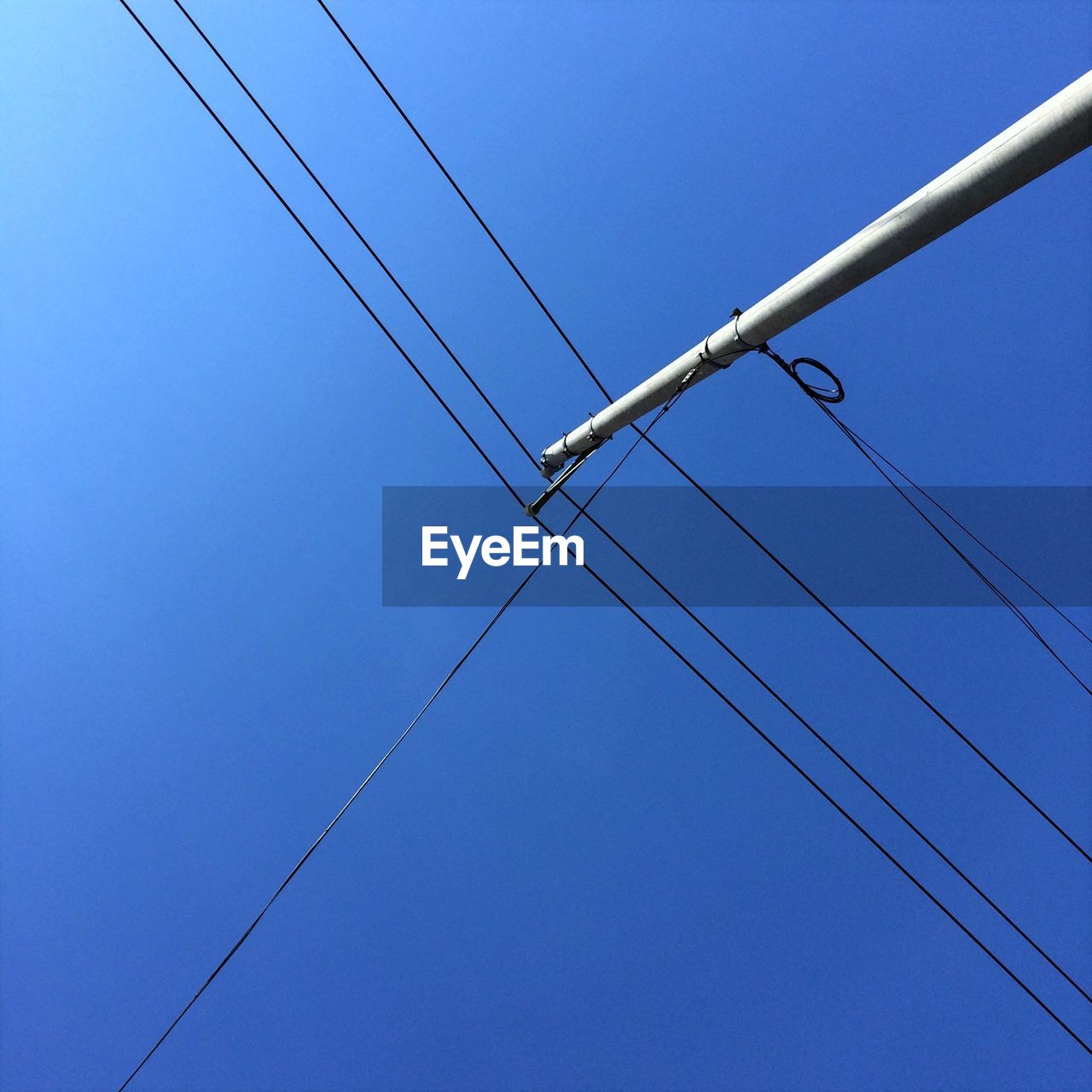 LOW ANGLE VIEW OF TELEPHONE POLE AGAINST CLEAR BLUE SKY