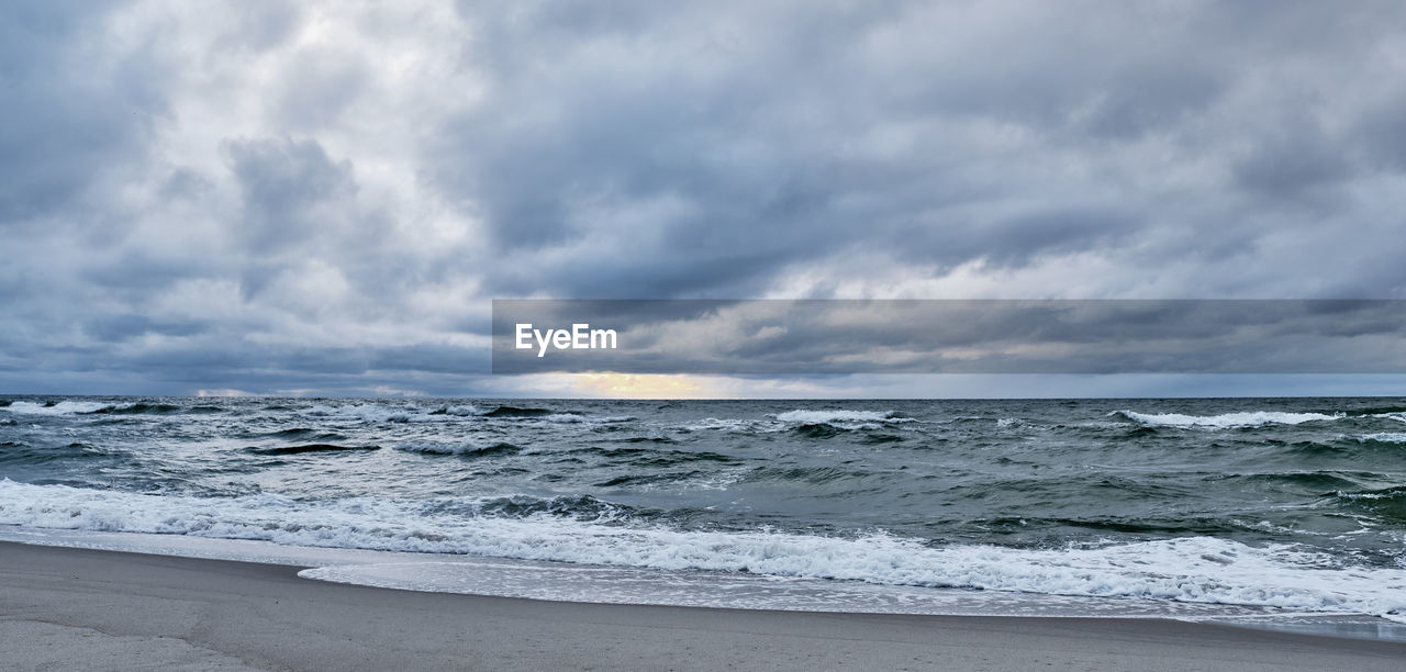 SCENIC VIEW OF BEACH AGAINST CLOUDY SKY