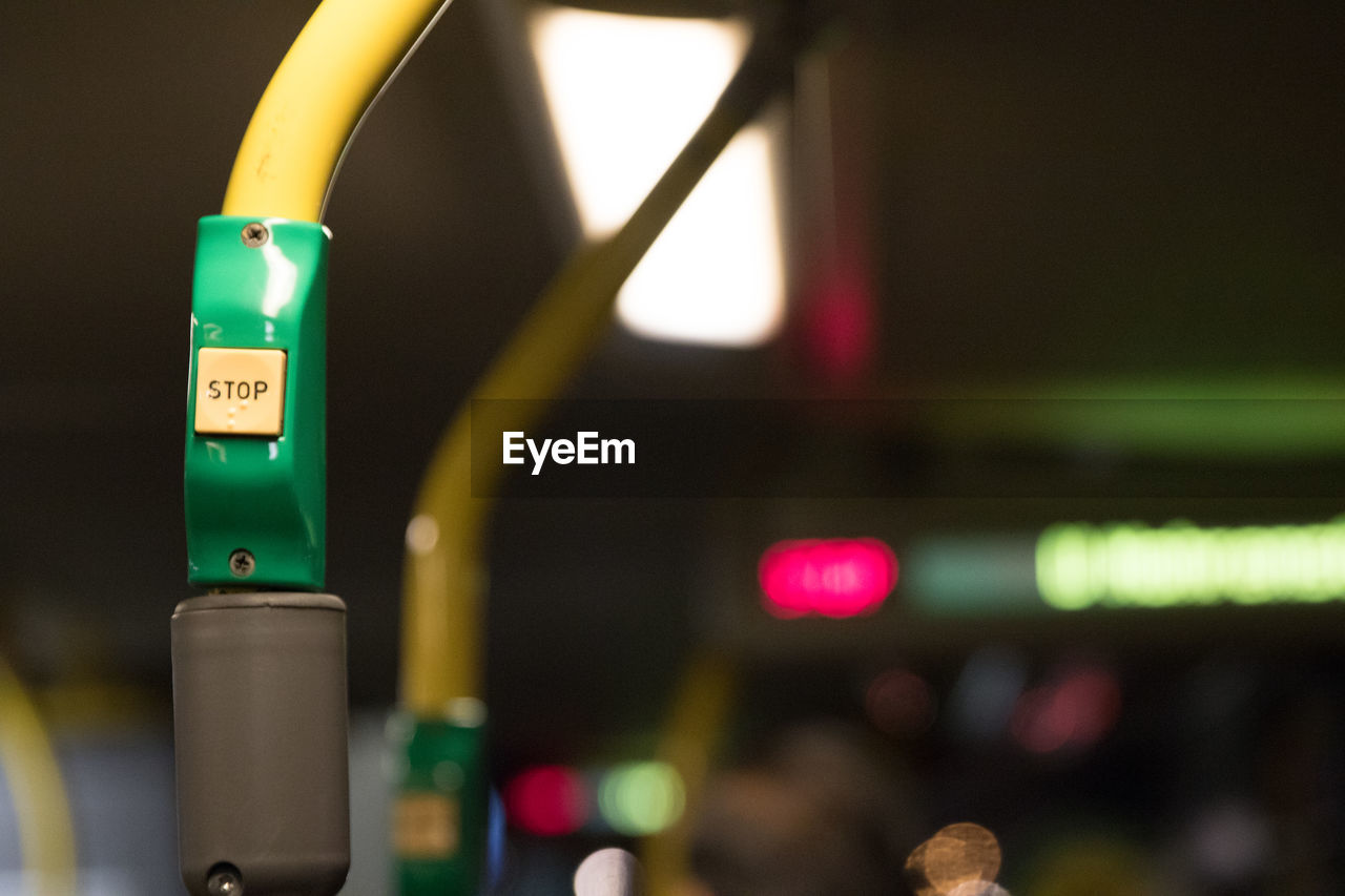 Close-up of stop push button on pole in illuminated bus